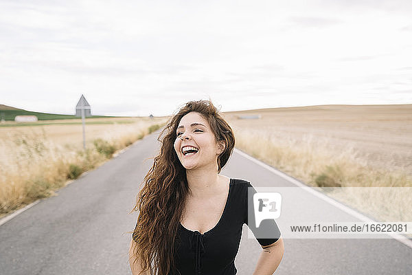 Lächelnde junge Frau auf der Straße stehend gegen den Himmel