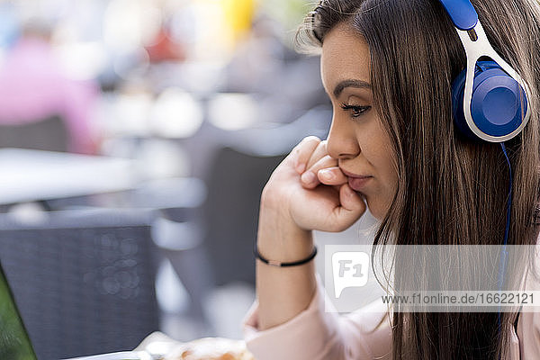 Nachdenkliche Geschäftsfrau mit Kopfhörern  während sie im Café sitzt
