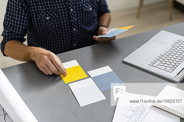 Architect choosing color swatch while sitting by desk at office