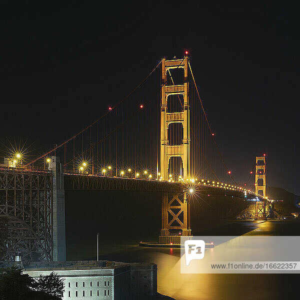 Night view of glowing Golden Gate Bridge over sea at San Francisco  California  USA