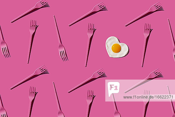 Pattern of pink plastic forks with single heart shaped fried egg