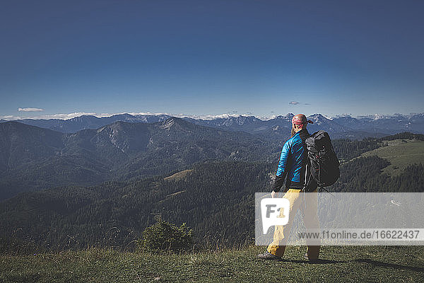Male hiker with backpack looking at mountains against clear sky  Otscher  Austria