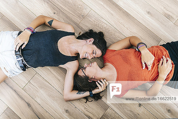 Smiling young friends lying down on floor at home