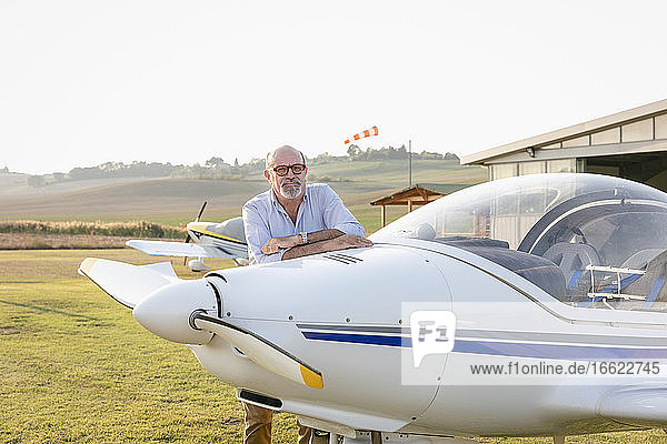Senior man with arms crossed standing at airfield