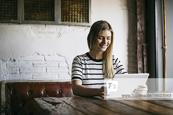 Mittlere erwachsene Frau  die ein digitales Tablet benutzt  während sie in einem Cafe sitzt