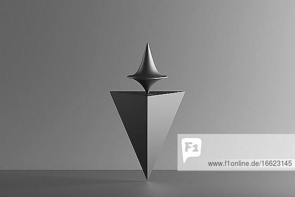 Dreidimensionales Rendering eines sich drehenden Metallkreisels auf einer auf dem Kopf stehenden geometrischen Pyramide