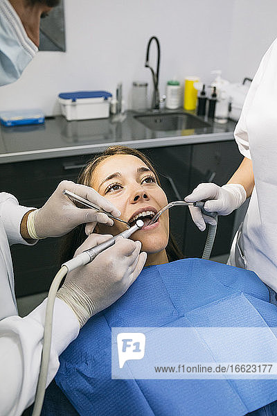Männlicher Zahnarzt bei der zahnärztlichen Behandlung einer Patientin mit Hilfe einer Assistentin in der Klinik
