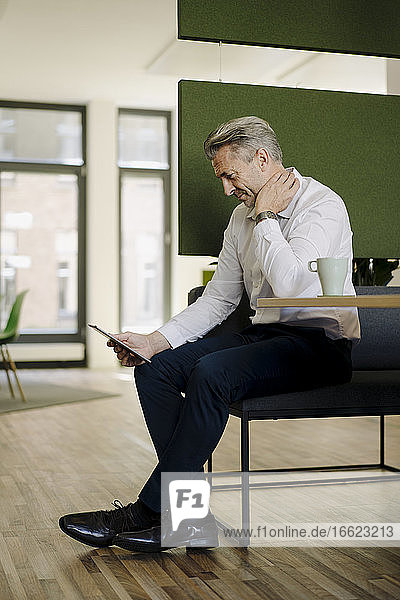 Man using digital tablet while sitting by table at office