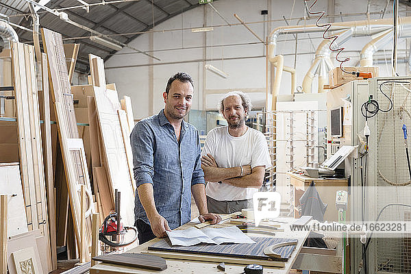 Smiling project manager standing by coworker in factory