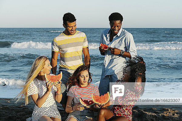 Freunde genießen beim Essen einer Wassermelone an einem sonnigen Tag