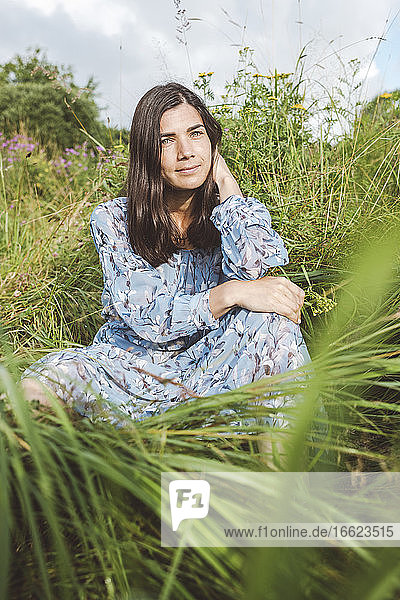 Mittlere erwachsene Frau inmitten von Pflanzen an Land sitzend