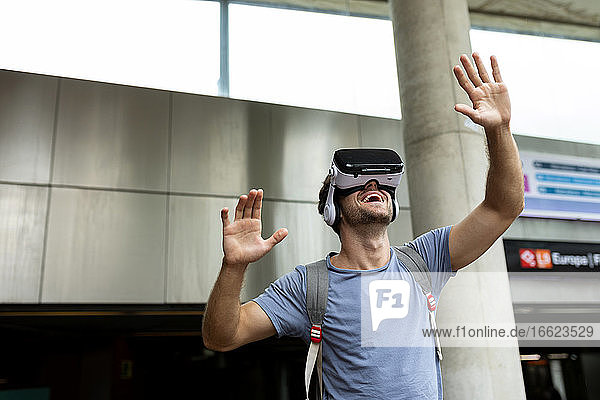 Smiling young male commuter enjoying virtual reality headset at subway station