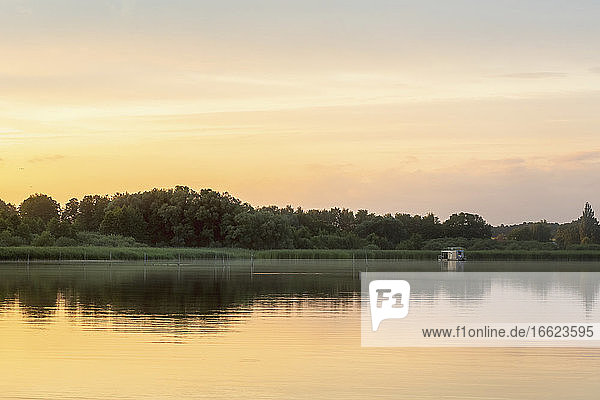 Fernblick auf ein Hausboot im See bei Sonnenuntergang