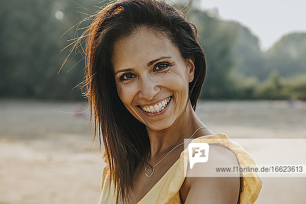 Lächelnde Frau am Strand stehend an einem sonnigen Tag