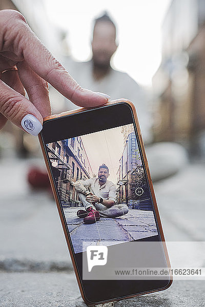 Frau fotografiert Mann mit Smartphone auf Gehweg in der Stadt