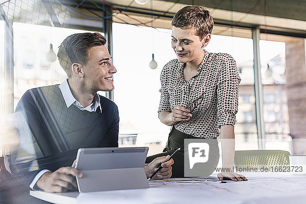Smiling business partners discussing at desk in office