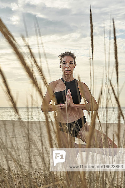 Frau übt Yoga im Stehen am Strand