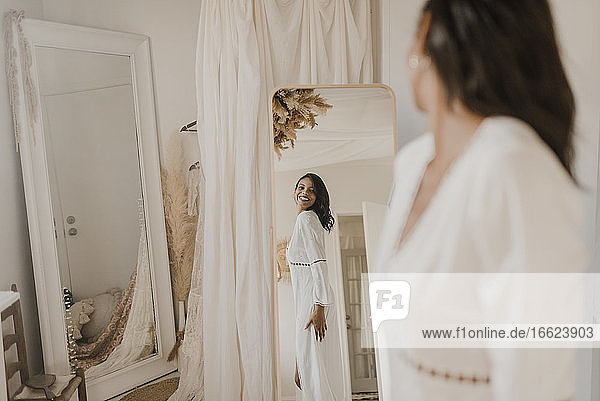 Junge Braut schaut in den Spiegel  während sie zu Hause steht