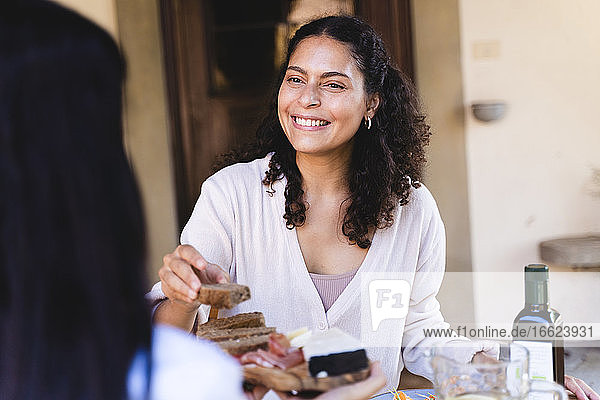 Woman having lunch with friend while sitting at back yard