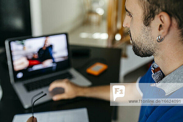 Junger Mann benutzt Laptop beim Lernen zu Hause