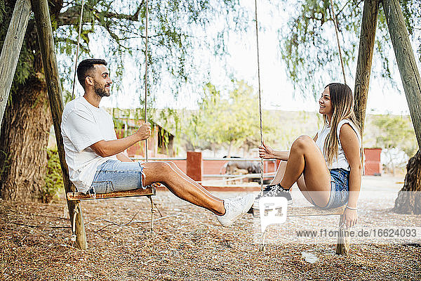 Junges Paar verbringt Zeit auf einer Schaukel in einem öffentlichen Park
