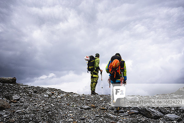 Männliche Freunde wandern auf einem Berg gegen den bewölkten Himmel im Stilfserjoch-Nationalpark  Italien