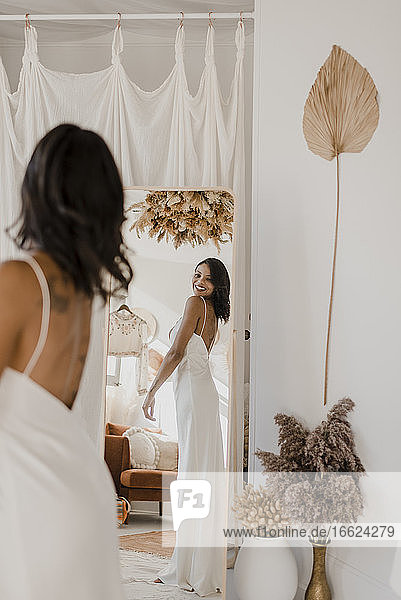 Bride looking in mirror while standing at home