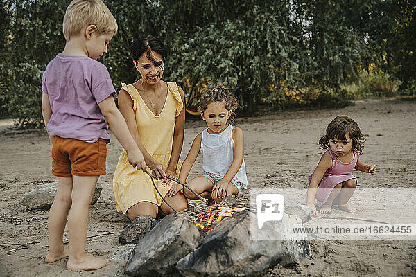 Mature woman and children making barbecue at beach