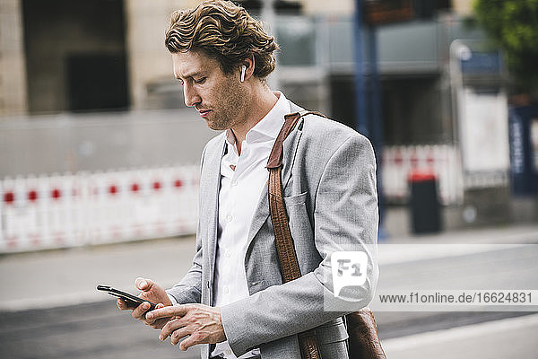 Businessman using mobile phone while standing in city