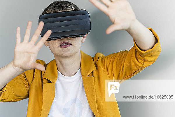 Nahaufnahme einer Geschäftsfrau  die durch einen Virtual-Reality-Simulator an der Wand eines Büros schaut