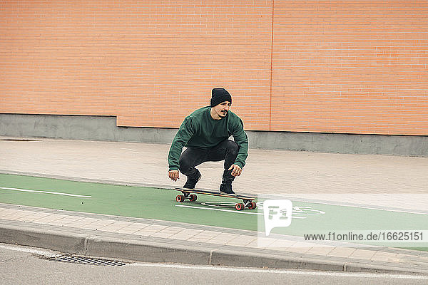 Junger Mann fährt mit dem Skateboard auf dem Fahrradweg
