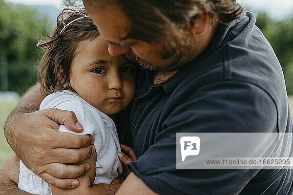 Vater umarmt Tochter,  während er im Garten sitzt