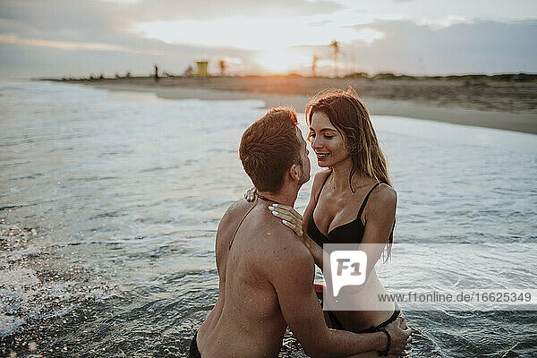 Pärchen in Badekleidung bei einer Romanze im Wasser am Strand