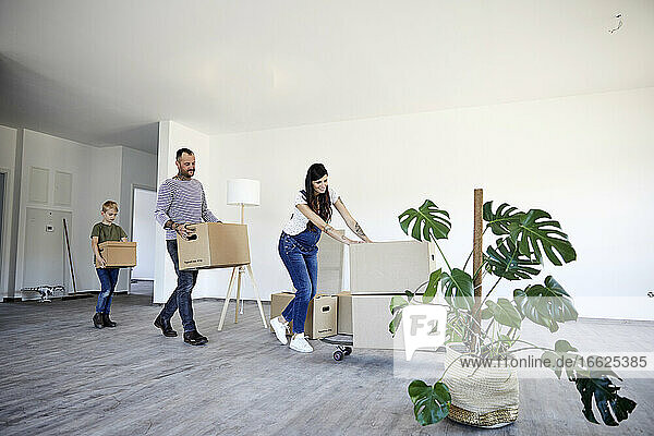 Familie justiert Kartons auf Skateboard im neuen Haus