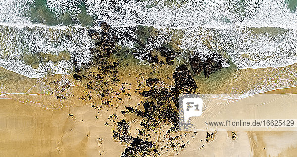 Luftaufnahme von Felsen am sandigen Küstenstrand