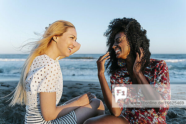 Lachende Freunde  die am Strand miteinander reden