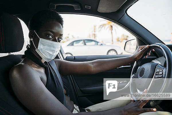 Frau mit Gesichtsschutzmaske beim Autofahren