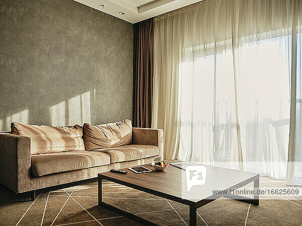 Hölzerner Couchtisch mit leerem Sofa in einem luxuriösen Hotelzimmer