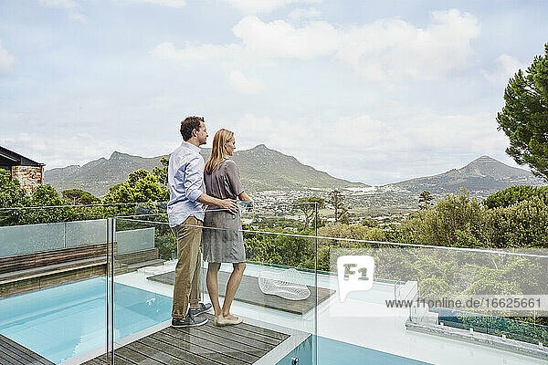 Stehendes Ehepaar mit Blick vom Balkon eines modernen Hauses