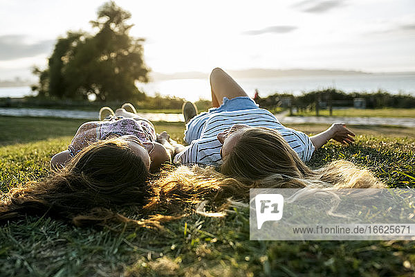 Junge Freundinnen entspannen sich auf einer Wiese und verbringen das Wochenende zusammen