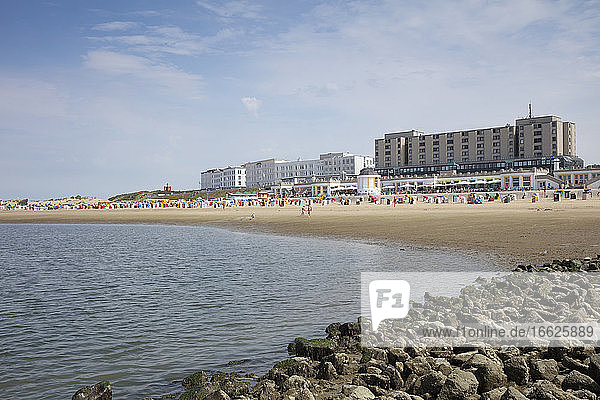Menschen genießen am Strand gegen Gebäude in der Stadt an einem sonnigen Tag