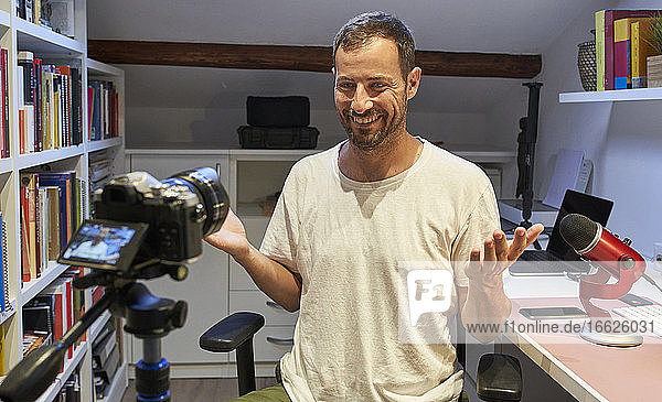 Lächelnder Mann  der von zu Hause aus ein Videotutorial mit der Kamera aufnimmt