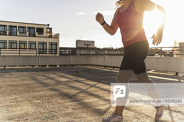 Weibliche Athletin läuft auf einer Gebäudeterrasse in der Stadt