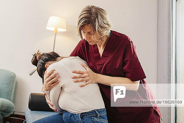 Physiotherapist helping woman for stretching
