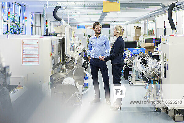 Geschäftsfrau und Geschäftsmann diskutieren über Maschinen in der Beleuchtungsindustrie