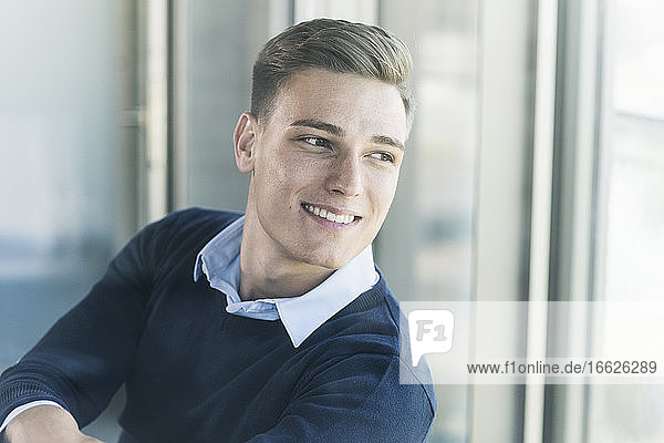 Close-up of thoughtful smiling male professional seen through window in office