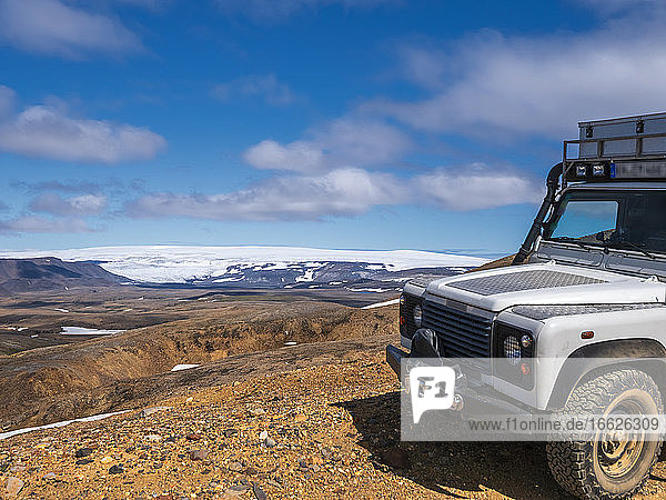Iceland  Southern Region  4x4 car parked in Kerlingarfjoll range with Langjokull icecap in distant background