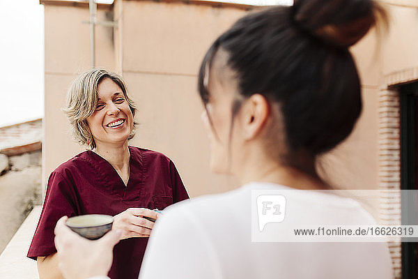 Lächelnde Physiotherapeutin im Gespräch mit einer Frau auf dem Dach