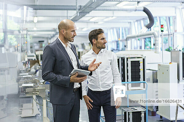 Confident male colleagues discussing while looking away at factory