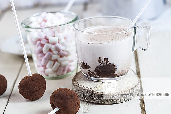 Close-up of hot chocolate with truffle lollipops and marshmallows on table at home